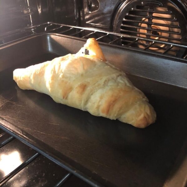 one butter croissant baking in an oven